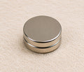 A 12mm by 3mm round neodymium magnet resting on a linen background